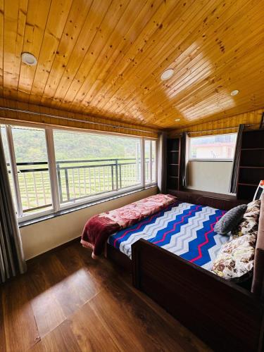 a bedroom with a bed in a room with windows at Dhauladhar Vista in Pālampur