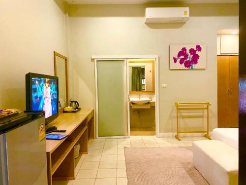 a room with a desk with a computer and a television at Spice & Sea Resort in Kata Beach