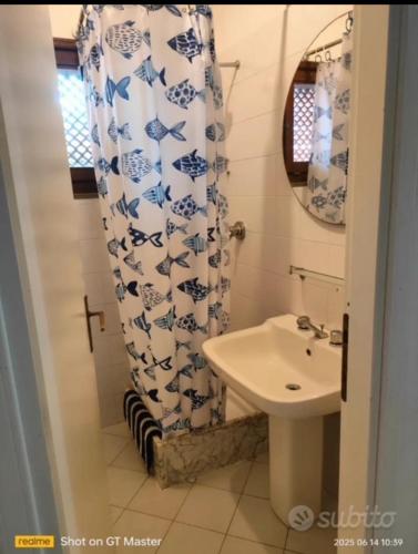 a bathroom with a sink and a shower curtain at Villa Clelia in Stintino