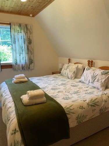 a bedroom with a bed with two towels on it at West Haven Lodge in Aultbea