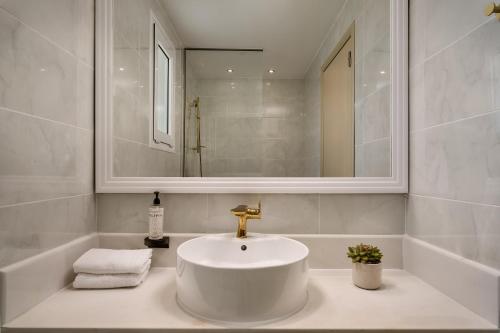 a white bathroom with a sink and a mirror at Sandy Villas Resort by Rizos Resorts in Línia