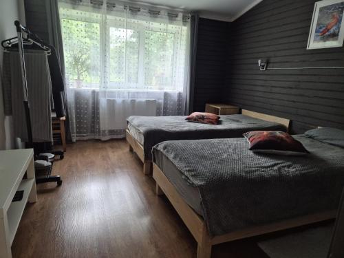 a bedroom with two beds and a window at KLĀNU MĀJA in Varakļāni