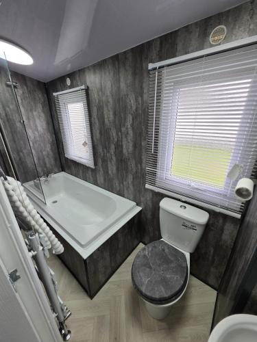 a bathroom with a tub and a toilet and a sink at Carlys Cosy Caravan in Cresswell