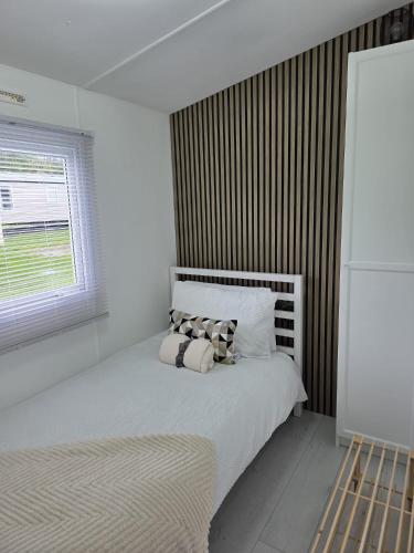 a white bedroom with a bed and a window at Carlys Cosy Caravan in Cresswell
