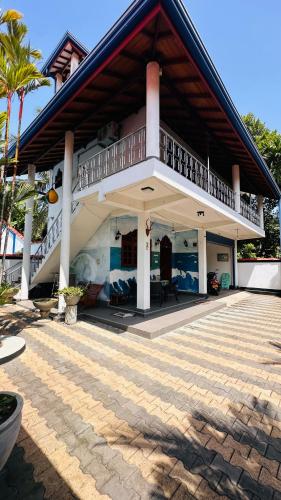 a house with a balcony on top of it at Chamo Villa by DrMocktail in Beruwala