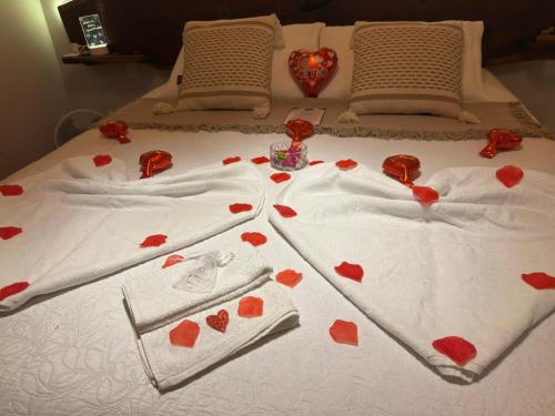 a bed with red hearts on the sheets at Chalé Recanto do Quilombo - MV in Camanducaia