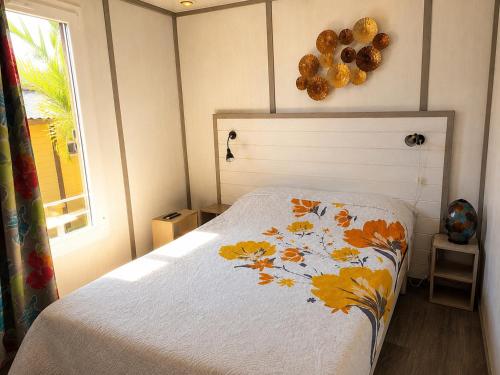 a bedroom with a bed with a flower blanket on it at Au Paradis de Peggy - Bungalow 5 pers - Village de la Pointe Faula in Le Vauclin