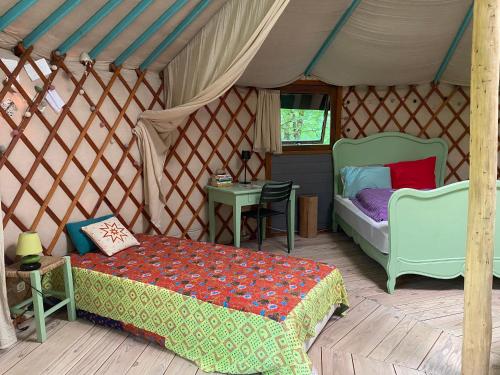 a bedroom with a bed and a table in a yurt at Les Jardins d'Yzorche in Saint-Bazile-de-la-Roche