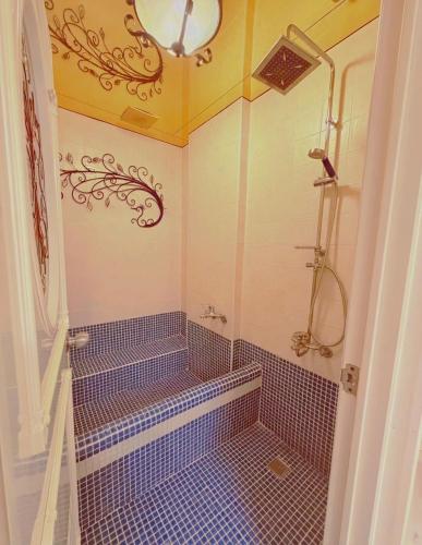 a bathroom with a shower with blue tile at 燈塔情人歐風海景民宿 in Eluan