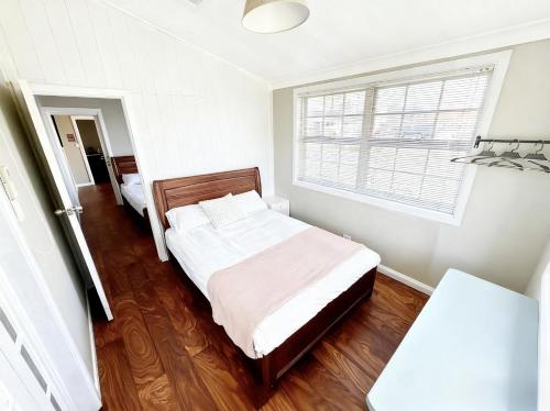 a bedroom with a bed and a window at Coffs Coastal Cabin, Central & Convenient in Coffs Harbour