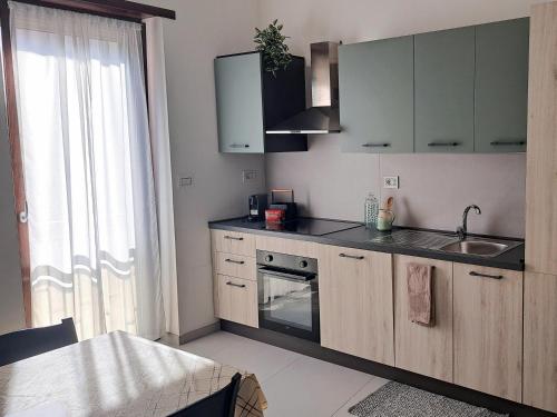 a kitchen with wooden cabinets and a sink and a window at Lettera 22 Apartment in Brindisi