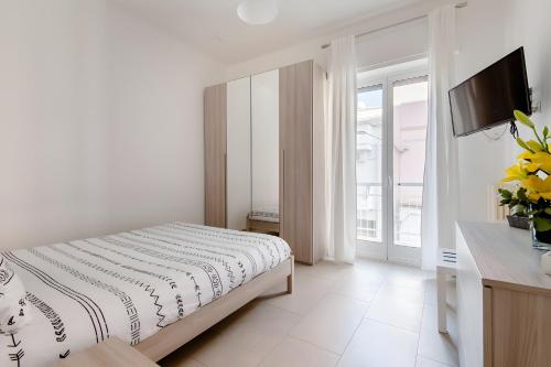 a white bedroom with a bed and a television at Scirocco Guest House in Brindisi