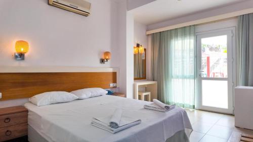 a bedroom with a large white bed with two towels at Konfor Suite Otel in Oludeniz
