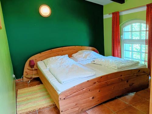 a bedroom with a wooden bed with a green wall at Ferien am Schloss - Wohnung 4 "der Hund", Ferienwohnung am Badesee in Behren-Lübchin