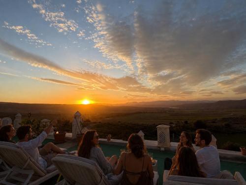 a group of people sitting around a pool watching the sunset at 1001-Nights Palace in Nebeur
