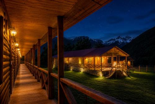 a wooden cabin with lights on the porch at night at Ushba Hill Panoramic Lodge Becho in Mestia