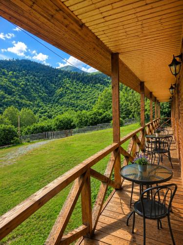 a deck with tables and chairs and a view of a field at Ushba Hill Panoramic Lodge Becho in Mestia