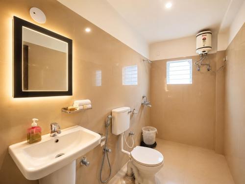 a bathroom with a sink and a toilet and a mirror at Hotel Puri Waves - Near Blue Flag Beach - Restautant, Parking & Spa in Puri