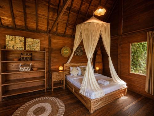 a bedroom with a bed with a mosquito net at Zen Tree House in Silebeng