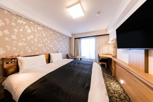 a hotel room with a bed and a flat screen tv at APA Hotel Kyoto Gion Excellent in Kyoto