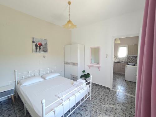 a bedroom with a white bed and a pink curtain at Tramonto Nel Delfini in Kini