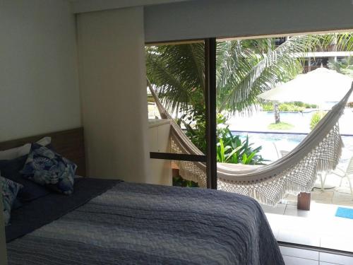 1 dormitorio con 1 cama y balcón con hamaca en Nannai Residence Flat, en Porto de Galinhas