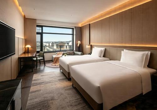 a hotel room with two beds and a television at Bristoria Hotel Yangzhou in Yangzhou