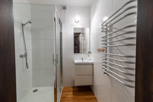 a white bathroom with a shower and a sink at Gościniec Lila in Mikołajki
