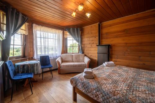 a bedroom with a bed and a couch and chairs at Gościniec Lila in Mikołajki
