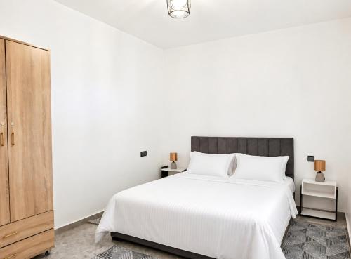 a bedroom with a white bed and a wooden cabinet at S1 Modern & Relax in Agadir