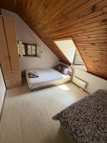 a attic bedroom with a bed and a wooden ceiling at Vila Jovicic in Popadić