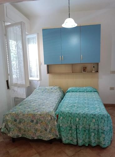 two beds in a room with blue cabinets at Villaedi in Marina di Bibbona
