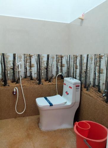 a bathroom with a toilet with a forest mural at Nature Nest In in Auroville