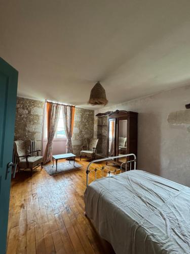 a bedroom with a bed and a chair and a window at Maison sur Coline in Lectoure