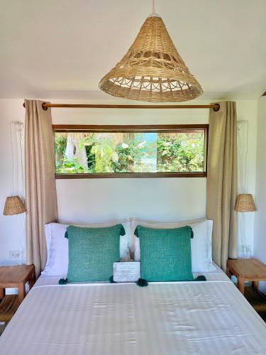 a bedroom with a bed with two green pillows and a window at Kalulushi Bungalows in Haad Pleayleam