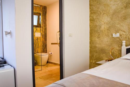 a bedroom with a bed and a bathroom with a toilet at Cataleya House in Oeşti-Pămînteni
