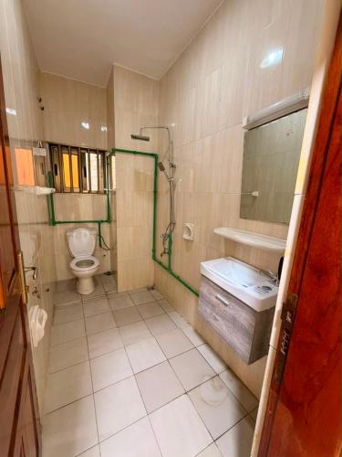 a bathroom with a toilet and a sink and a mirror at Chez Gero Aeroport in Cotonou