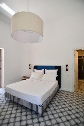 a bedroom with a large white bed with a large light fixture at Le Dimax in Sant'Agnello