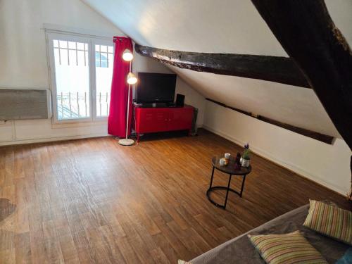 a living room with a couch and a tv in a attic at Le Petit Attique de Versailles in Versailles