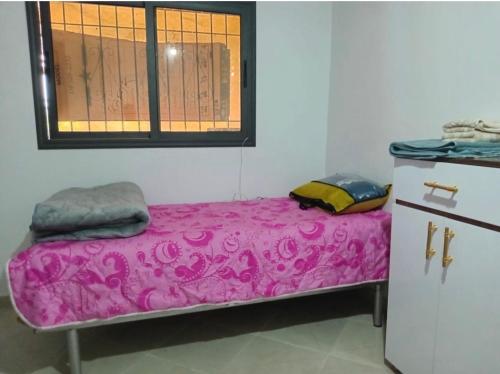 a room with a pink bed with a window at Dar Calme Takad in Ben Guemoud