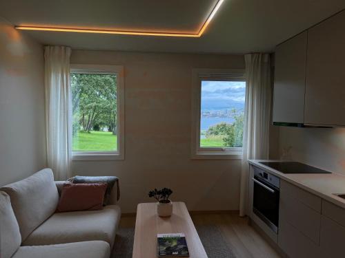 a living room with a couch and a table and two windows at Parkside apartment in Narvik