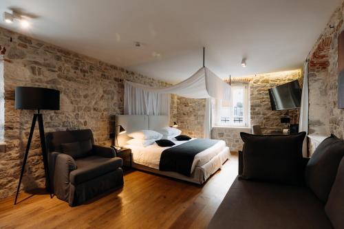 a bedroom with a bed and a couch and a chair at Murum Heritage Hotel in Split