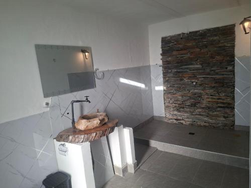 a bathroom with a television and a stone wall at Alojamiento Campestre Barachel in Pamplona