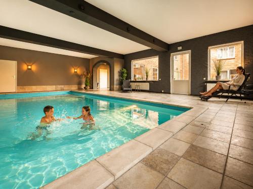 two children are playing in a swimming pool at Hotel de Landmarke Ootmarsum in Groot-Agelo
