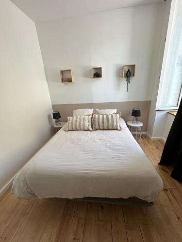 a bedroom with a large bed with white sheets and wood floors at Molène Centre Ville Lannion in Lannion