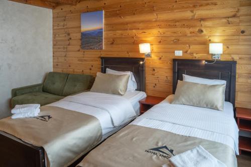 zwei Betten und eine Couch in einem Zimmer mit Holzwänden in der Unterkunft Hotel Enigma in Žabljak