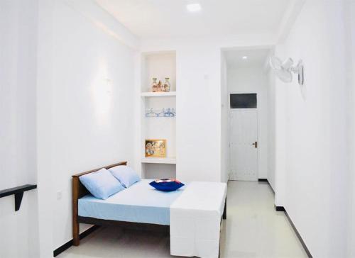 a small bedroom with a bed and a white wall at Lodge 52 Negombo in Negombo