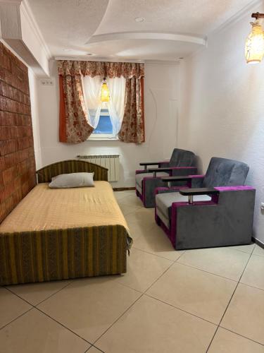 a bedroom with two beds and chairs and a window at Пані Анна in Kamianets-Podilskyi