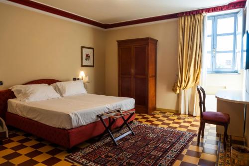 a bedroom with a bed and a table and a window at Albergo Castiglione Langhe in Castiglione Tinella