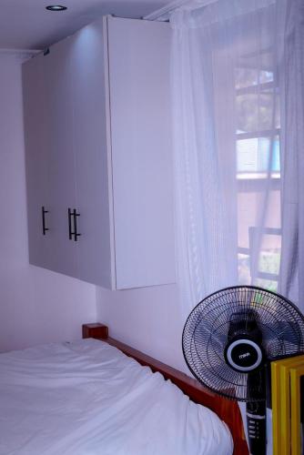 a bedroom with a bed and a window with a fan at MPD Deluxe Suites in Kakamega
